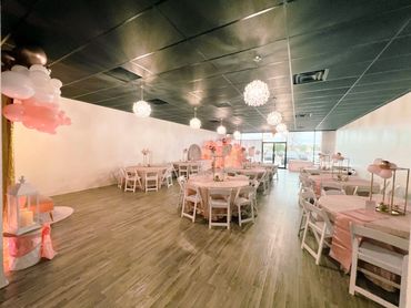 Elegant event space with pink and white decorations and chandeliers.