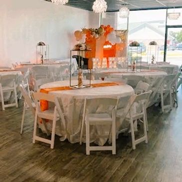 Venue decorated for a baby shower in the theme "A Little Cutie is on the Way!" with orange and white