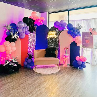 Colorful sweet 16 birthday party setup with balloons and a pink couch.
