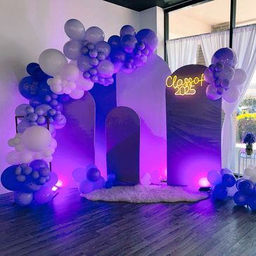 Purple-themed graduation decoration with balloons and 'Class of 2025' sign.