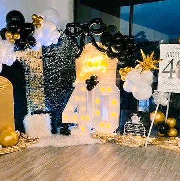 Elegant 40th birthday party setup with black, white, and gold decorations.