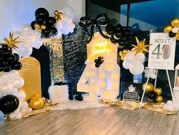 Elegant 40th birthday party setup with black, white, and gold decorations.