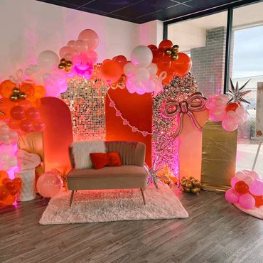 Valentine's Day themed photo booth with balloons and cozy seating.