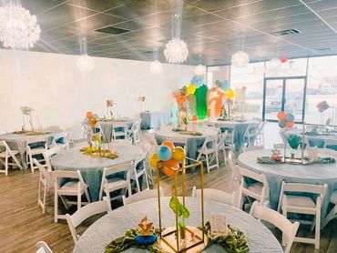 Brightly decorated event space with round tables and balloon centerpieces.