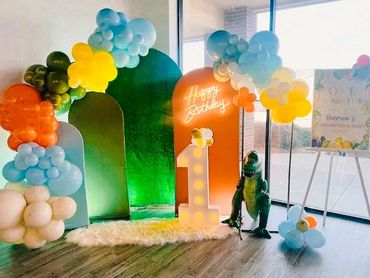 Colorful balloon arch and dinosaur decor for a first birthday party.