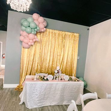 Elegant wedding table setup with gold backdrop and pastel balloons.