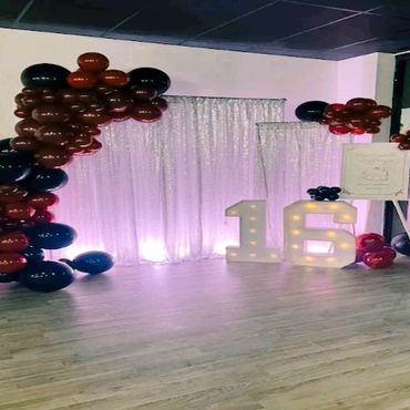 Sweet sixteen birthday party backdrop with balloons and marquee numbers.