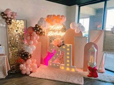 Elegant 21st birthday party setup with balloons and illuminated numbers.