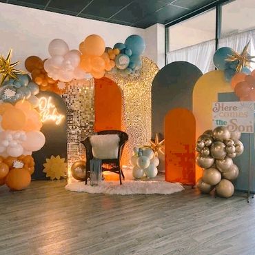 Colorful baby shower setup with balloons and a cozy chair.