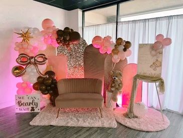 A cozy teddy bear-themed photo setup with balloons and soft lighting.