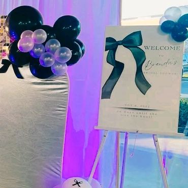 Elegant baby shower welcome sign with black and white balloon decorations.
