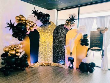 Elegant black, gold, and white balloon decor with a welcome sign for an engagement celebration.