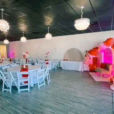 Elegant event space with white tables, chairs, and colorful balloon decorations.