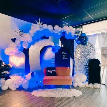A dreamy moon-themed photo booth setup with balloons and cozy seating.