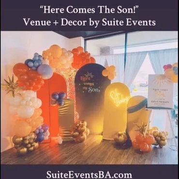 Colorful balloon arch and decorative panels for a 'Here Comes The Son!' event setup.