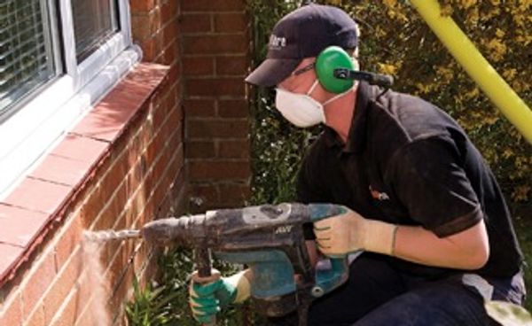 Man installing cavity wall insulation.