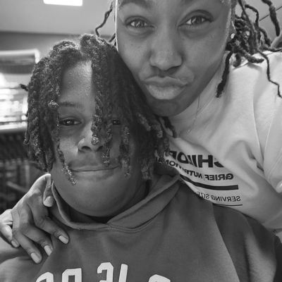 Two friends posing closely together, smiling and making a playful face.