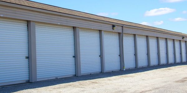 Row of closed white storage unit doors at a self-storage facility.