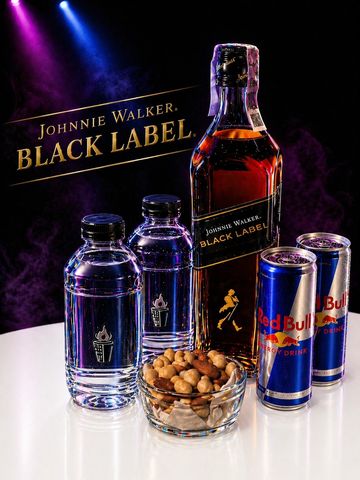 Johnnie Walker Black Label whisky with mixers and nuts on a table.