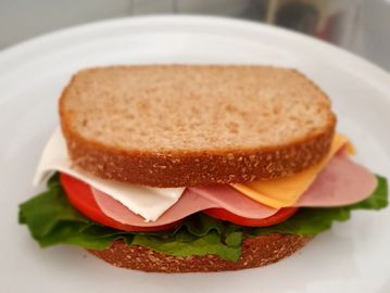 Sándwich de jamón con queso blanco y amarillo acompáñalo de lechuga, tomate y aguacate.