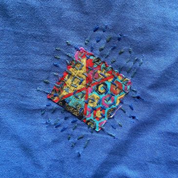 Colorful embroidery patch on blue fabric.