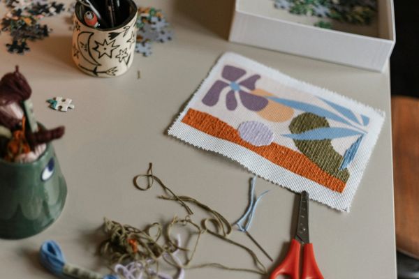 A crafting workspace with embroidery, scissors, and thread on a table.