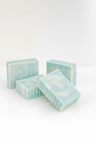 Four handmade blue and white marbled soap bars with ridged edges.