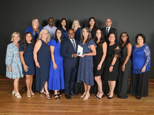 Group of professionals posing indoors with an award.