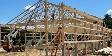 Barndominium post frame pole barn structure building with permacolumn 3 ply posts, trusses being set