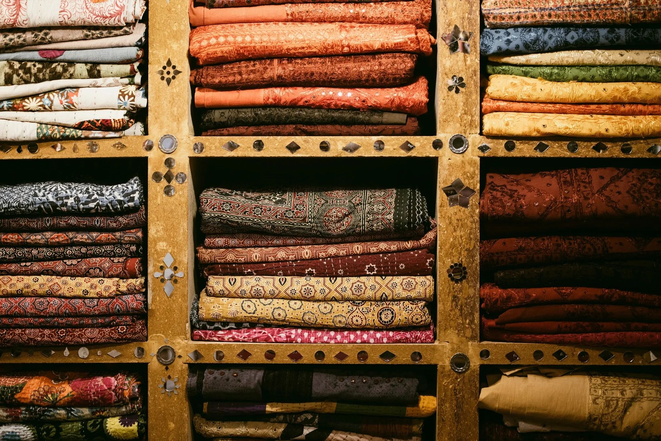 Colorful patterned fabrics arranged on shelves.