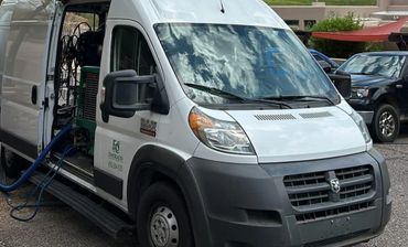 White service van with open side door and equipment inside.