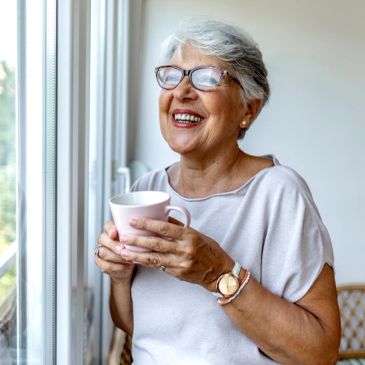 Mulher idosa feliz segurando uma caneca.