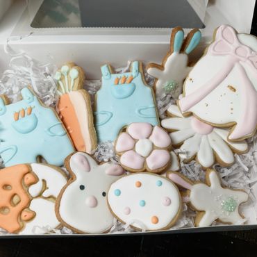 Decorative Easter-themed cookies in pastel colors inside a white box.
