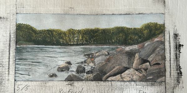 A serene lakeside scene with rocks and trees under a clear sky.