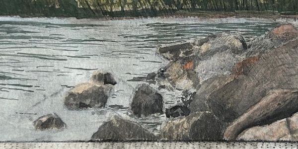 A serene lakeside scene with rocks and trees under a clear sky.