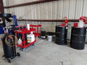 Oil change equipment including drums, carts, and containers in a workshop.