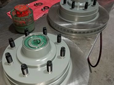 Two metal automotive brake rotors with studs on a workbench.