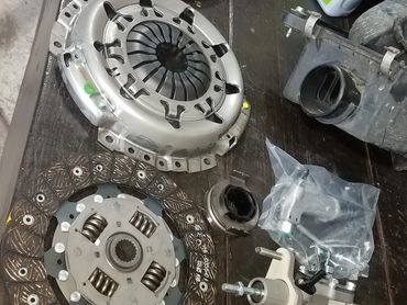 Car clutch components and manual transmission fluid on a workbench.