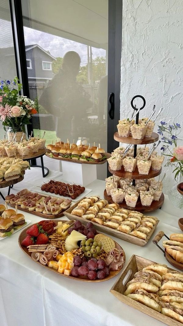 A table filled with assorted sandwiches, snacks, and fruit platters for a party.