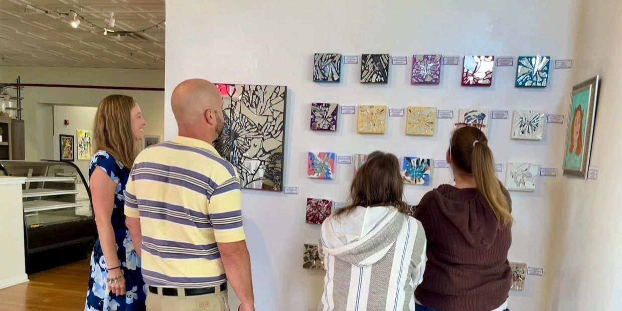 Group of people contemplating the Gaslighting wall at Breaking the Silence exhibition.