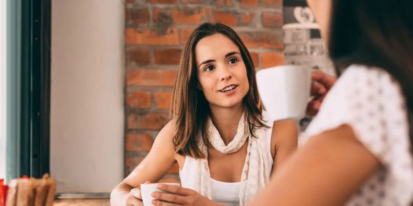 Two women having coffee and chatting in a cozy cafe.