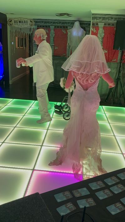 Bride and groom dancing on a glowing floor at a Halloween-themed wedding.