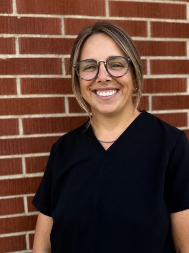 Smiling woman wearing glasses and black outfit.