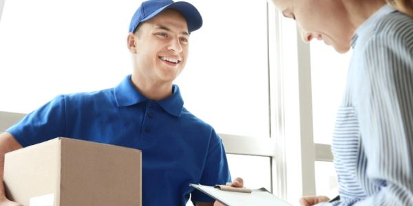 Delivery person handing over a package to a smiling woman.