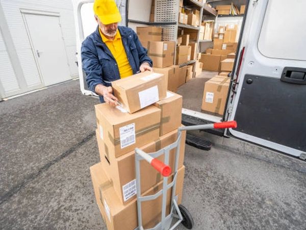 Delivery worker loading boxes onto a hand truck from a van.