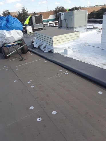 A rooftop with HVAC units and construction materials.