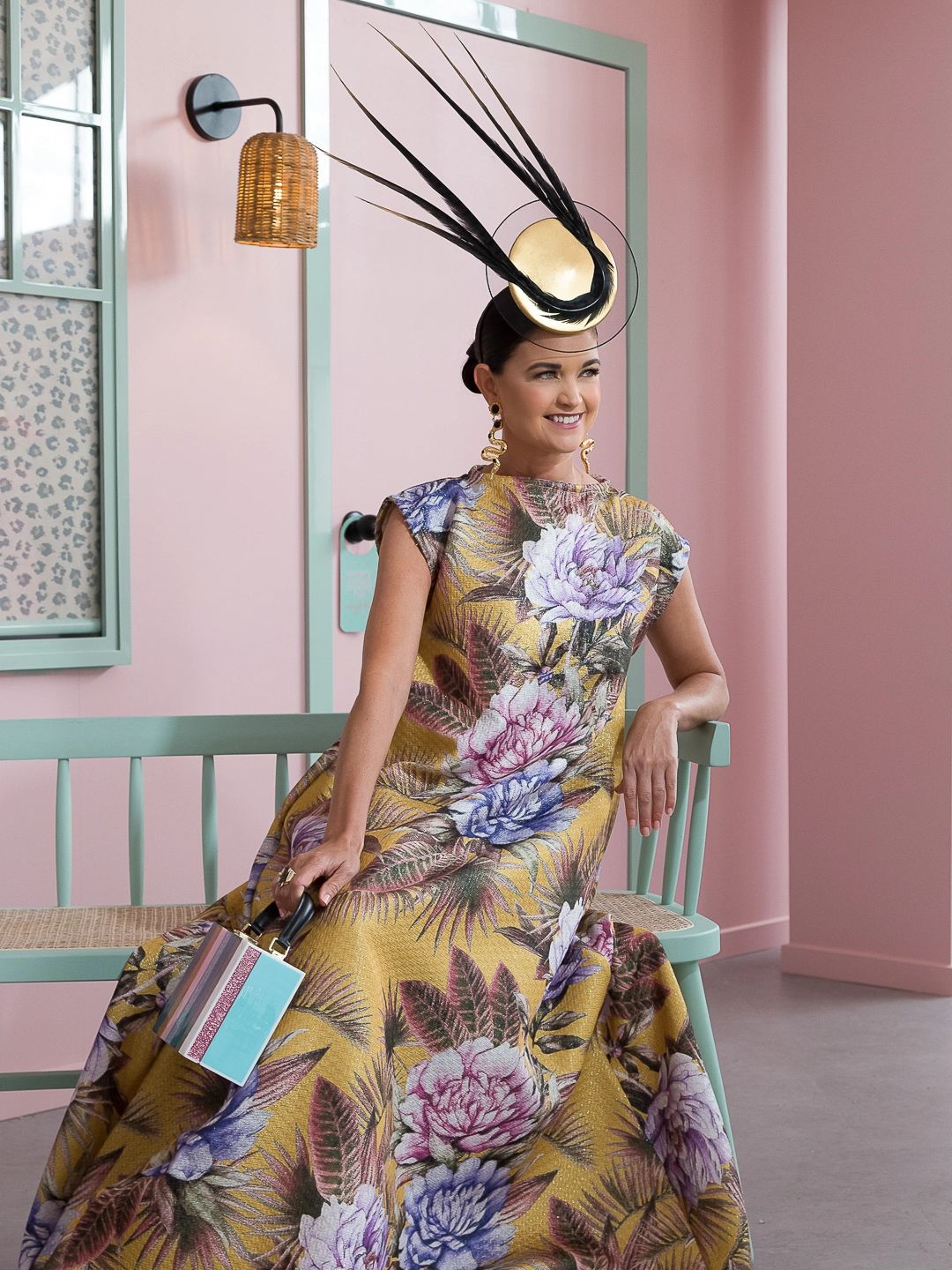 Peacock Millinery client sitting in wearing luxurious custom designed headwear.