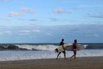 Two surfers walking on the beach with surfboards.