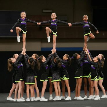 Young cheerleaders performing a group stunt in matching uniforms.