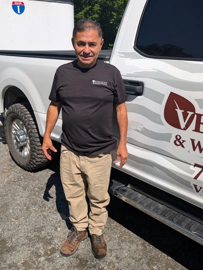 Man standing beside a white truck with company branding.